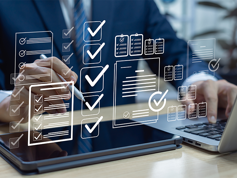 Zu sehen ist eine Person am Laptop und am Tablet wobei digitale Grafiken über den Geräten schweben