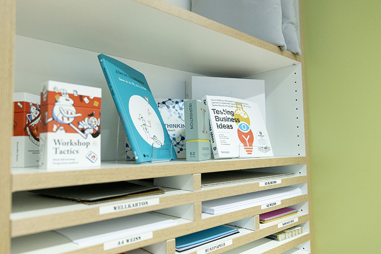 Ein Close-up von sieben Bücher im Regal. Unterhalb sind verschiedene Arte Papier verfügbar.